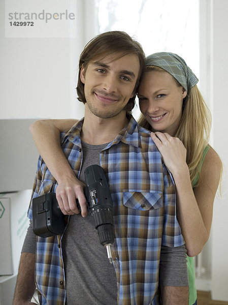 Woman embracing man  holding drill