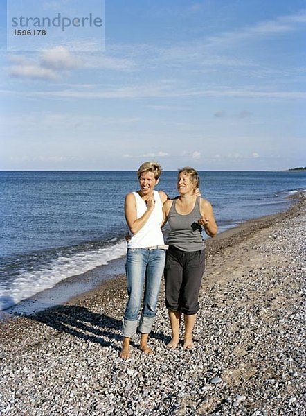 Zwei lachende Frauen am Strand.