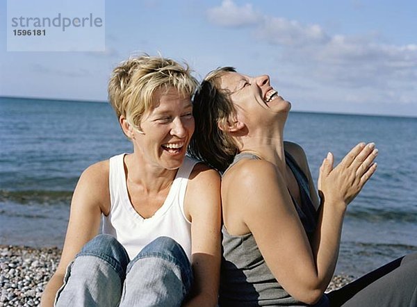 Zwei lachende Frauen am Strand.