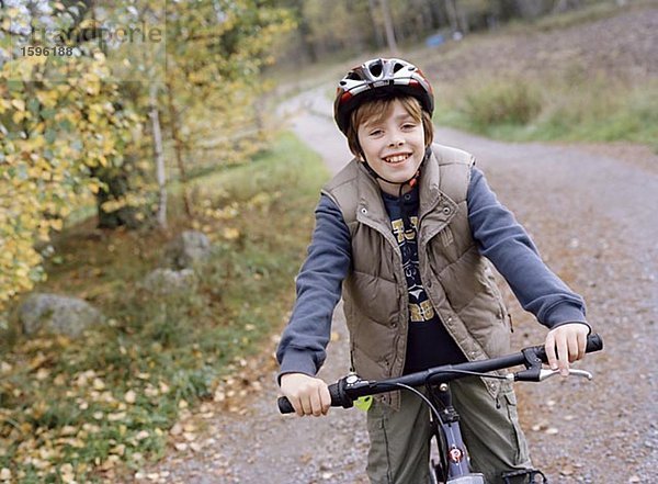 Ein Junge auf Schotterweg Radfahren.