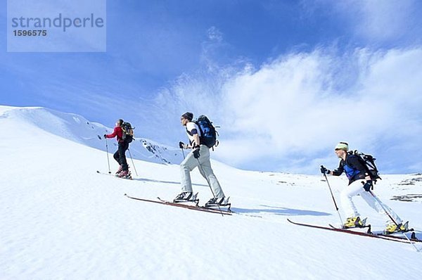 Drei Skifahrer der Skipiste Storulvan Jamtland Schweden hinauf.