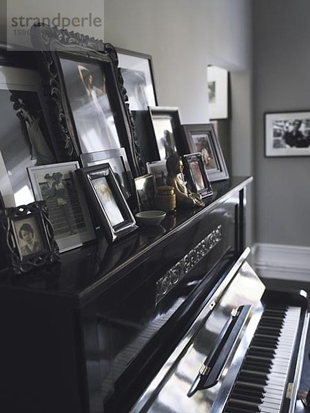 Eine Auflistung von Familienfotos platziert auf einem Klavier.
