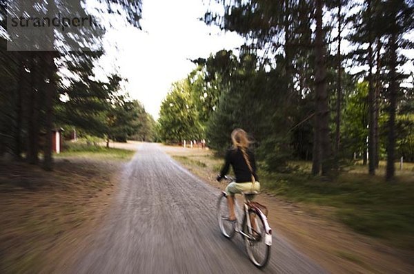 Ein Mädchen Radfahren auf einer Landstraße.