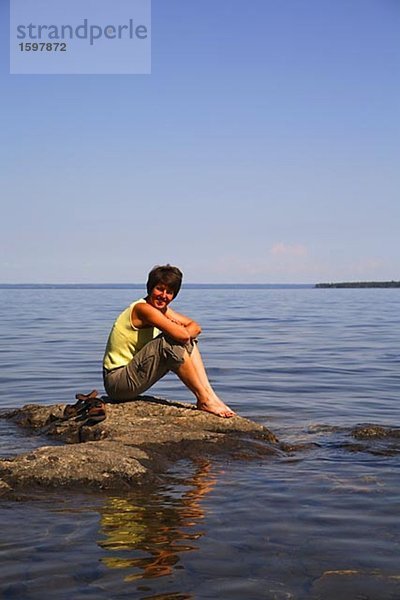 Frau sitzend auf einem Felsen Storsjon Jamtland Schweden.