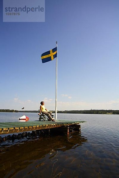 Skandinavischen Frau sitzt auf einer Bootssteg Jämtland Schweden.
