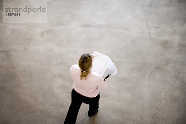 Eine Frau trägt einen Haufen von Papier in einem Büro Sicht aus Schweden.