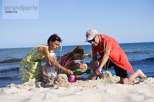 Zwei Erwachsene und zwei Kinder Gebäude ein Sand Schloss Oland Schweden.