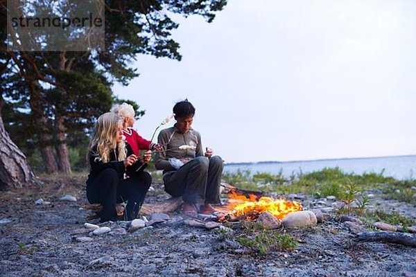 Eine skandinavische Frau und zwei Mädchen sitzen von einem Lager Feuer Oland Schweden.