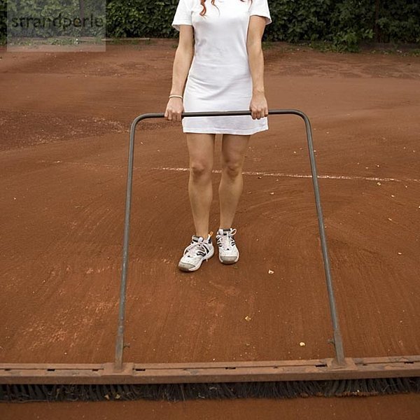 Eine Frau Vorbereitung einen Tennisplatz.