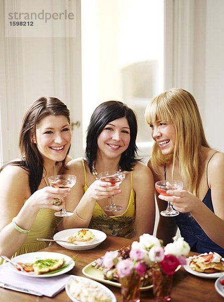 Drei junge Frauen bei einem Abendessen Schweden lächelnd.