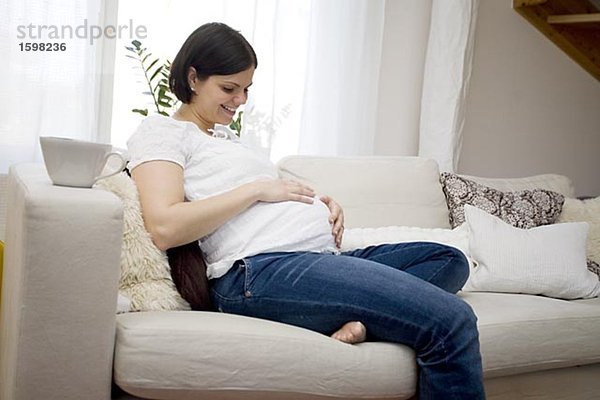 Eine schwangere Frau sitzt in einem Sofa Schweden.