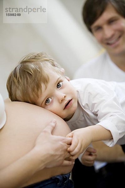 Ein kleines Kind eine schwangere Frau Magen Schweden anhören.
