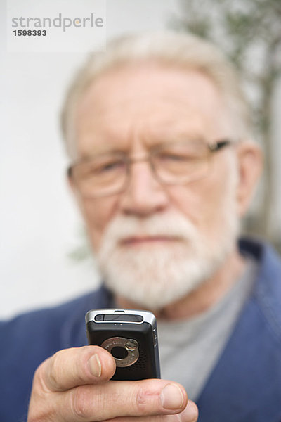 Ein älterer Mann mit einen Handy.