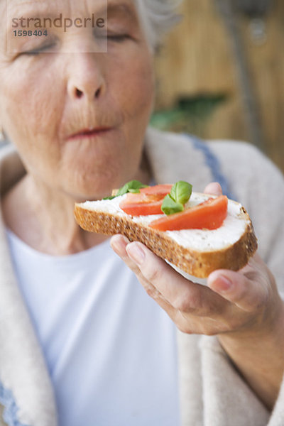 Frau Essen einen Sandwich mit Käse  Tomaten und Basilikum Schweden.