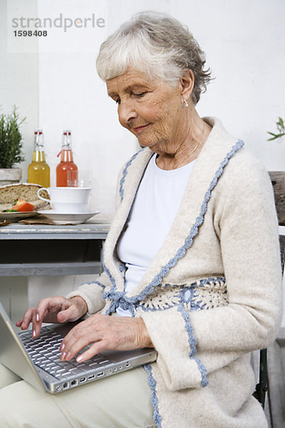 Eine ältere Frau Schreiben auf ihrem Computer Schweden.