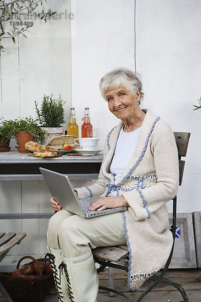 Eine ältere Frau Schreiben auf ihrem Computer Schweden.