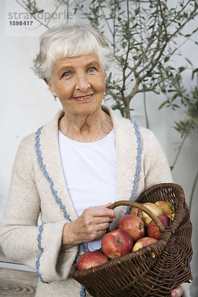 Frau hält einen Korb mit Äpfeln Schweden.