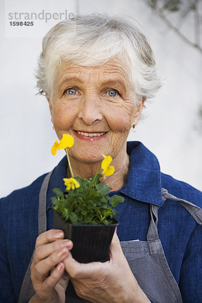 Eine ältere Frau hält eine Blume Schweden.