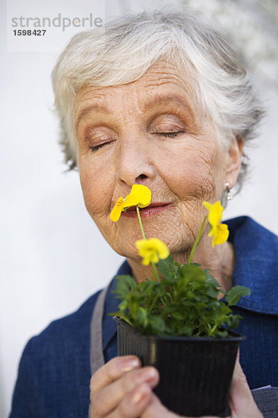 Eine ältere Frau hält eine Blume Schweden.