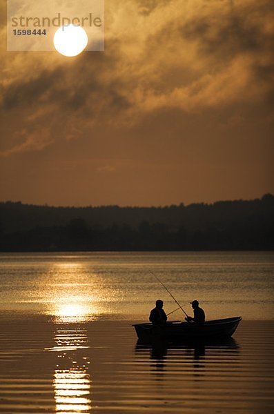 Zwei Personen sitzen in einem Boot Fischen am Nacht Mariefred Schweden.