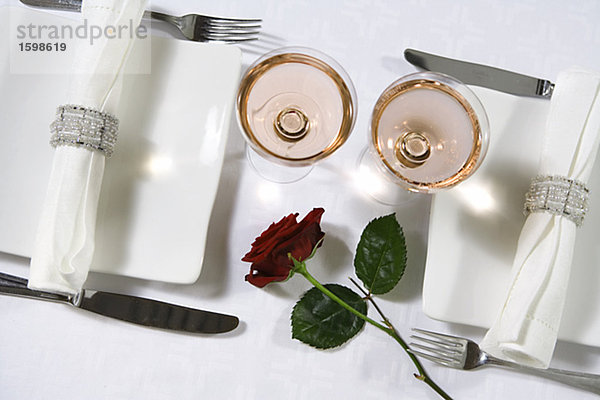 Ein gedeckter Tisch mit einer roten Rose.