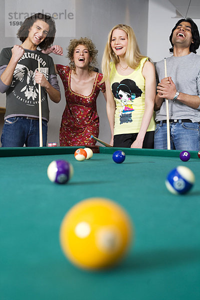 Vier Menschen Standing zusammen Lachen von einem Pocket Pool-Tisch.