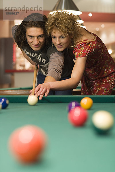 Ein Mann und eine Frau Pocket Billard spielen.