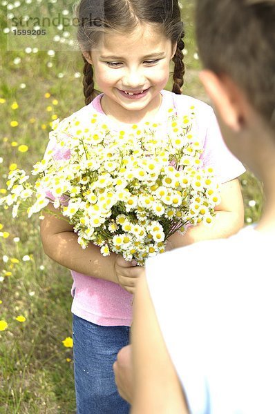 Mädchen Blumenstrauß zu jungen im Feld