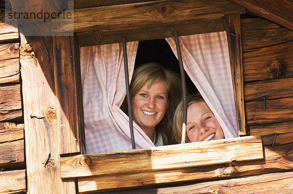 Zwei Frauen in der Almhütte  die aus dem Fenster schauen