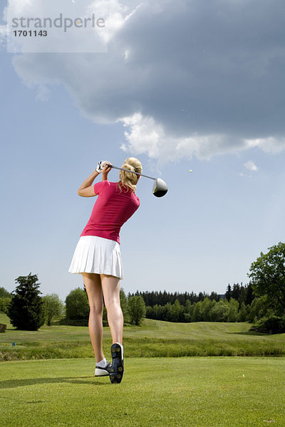 Junge Frau beim Golfen  Rückansicht