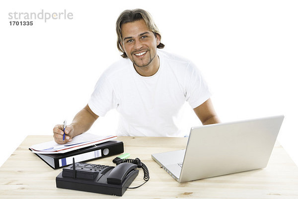 Mann am Schreibtisch mit Ordner  Laptop und Telefon  Nahaufnahme