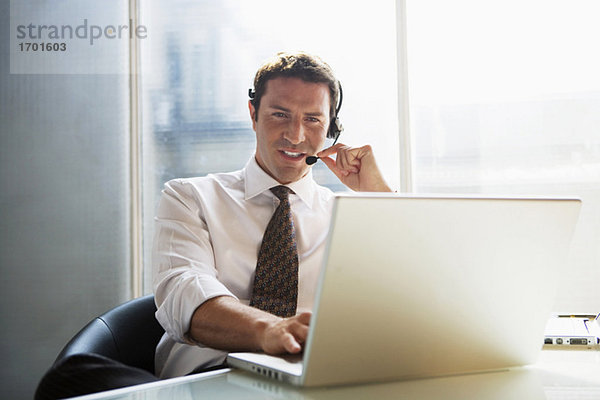 Business man sitting at desk  using head set