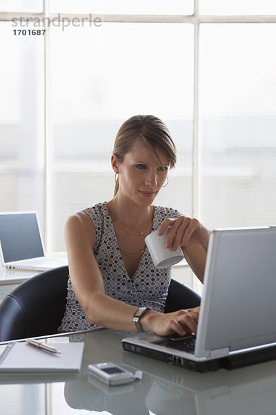 Frau mit Laptop  Haltebecher