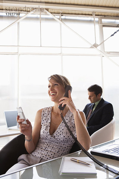 Business woman phoning  male colleague in background