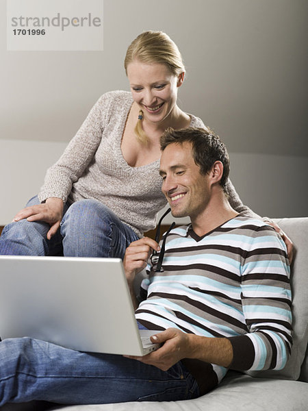 Paar auf dem Sofa sitzend  mit Laptop