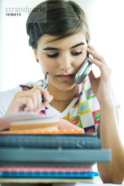 Teenagerin mit Hausaufgabenstapel  Handy und Haltestift