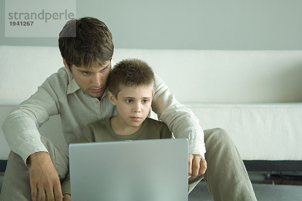 Junge und Vater benutzen gemeinsam einen Laptop