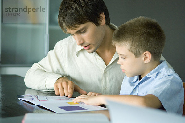 Mann hilft dem Jungen bei den Hausaufgaben