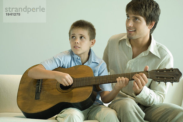 Mann  der dem Jungen beibringt  Gitarre zu spielen.