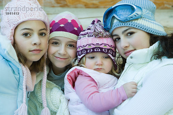 Drei Mädchen mit Kleinkind  alle mit Wintermänteln und Hüten  Portrait