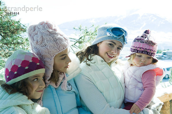 Drei Teenager- oder Kindermädchen mit Kleinkind in den Bergen  alle mit Wintermänteln und Hüten  Portrait