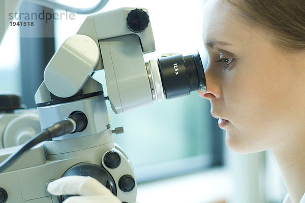 Junge Wissenschaftlerin beim Blick durchs Mikroskop  extreme Nahaufnahme