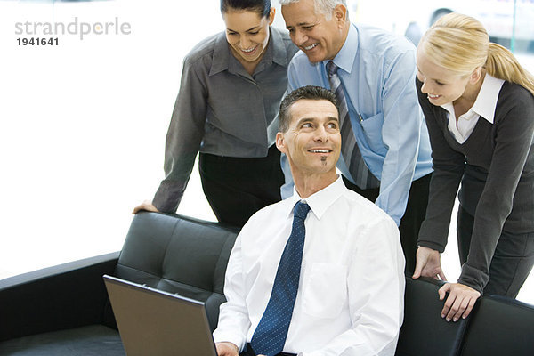 Geschäftsmann mit Laptop-Computer  lächelnd  Mitarbeiter über die Schulter schauend