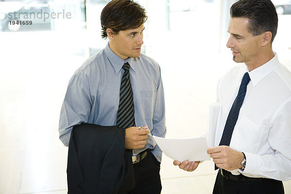Zwei Geschäftsleute schauen sich an  diskutieren  ein Holding-Dokument