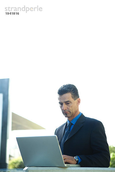 Geschäftsmann im Freien sitzend  mit Laptop-Computer  Taille oben