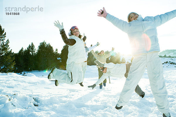 Junge Freunde springen in der Luft  bekleidet mit Winterkleidung  volle Länge