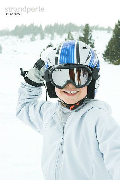 Junge mit Schneeball  gekleidet in Skikleidung  lächelnd vor der Kamera