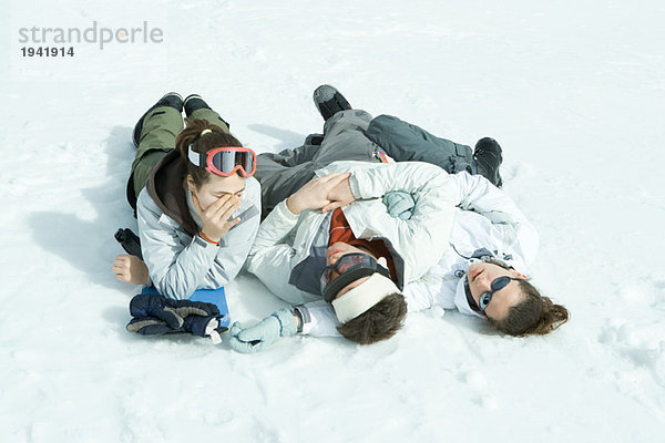 Drei junge Freunde im Schnee liegend  ein Kopf haltend