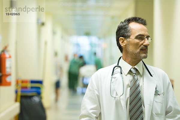 Männlicher Arzt schaut weg  Krankenhausflur im Hintergrund