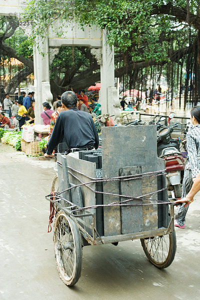 China  Provinz Guangdong  Mann  der Waren mit Rikscha auf den Straßenmarkt bringt.